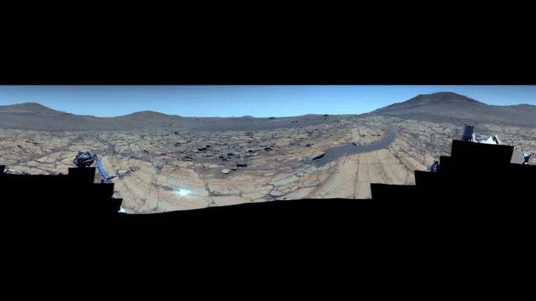Panoráma z lokality „Falbreen“ – úchvatná mozaika složená ze 96 snímků, pořízených 26. května 2025, zachycuje neobvykle čistou marťanskou oblohu s tóny modré (v upravené verzi) i červené (v přirozené barevnosti).