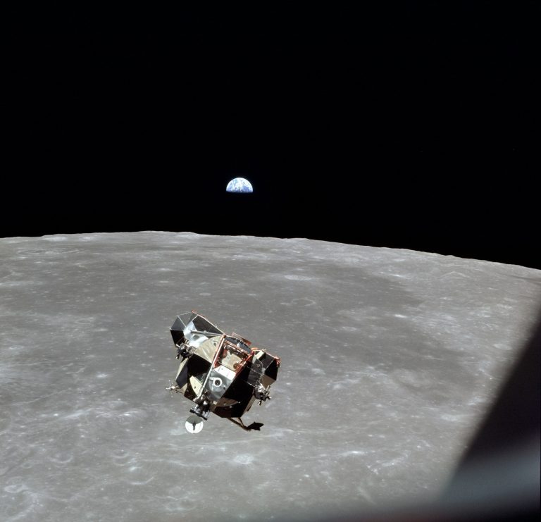 Eagle se vrací k velitelskému modulu Columbia, Na pozadí září vycházející Země.