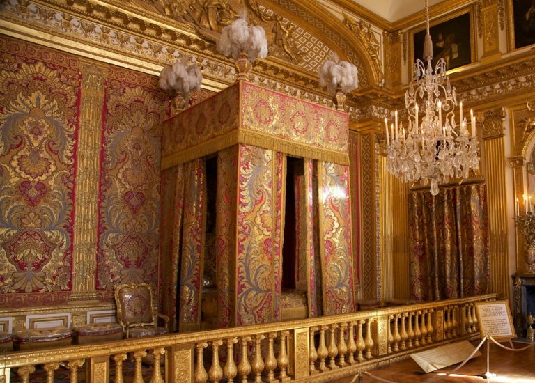 Jeho postel ve Versailles je nákladně zdobená.