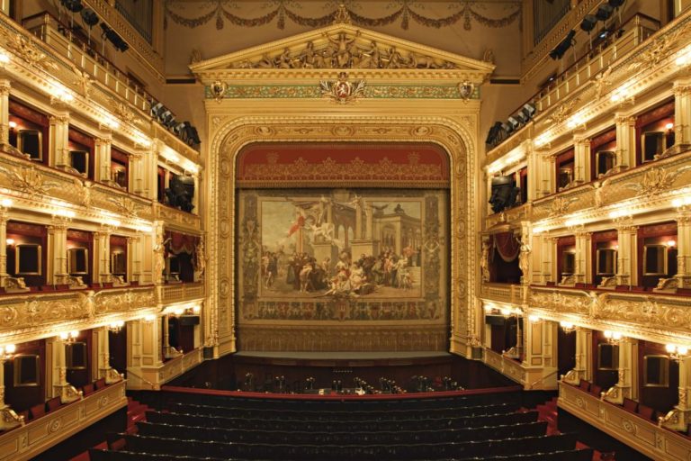 Hynaisova opona nahradila oponu malíře Františka Ženíška, která padla za oběť požáru divadla v roce 1881.