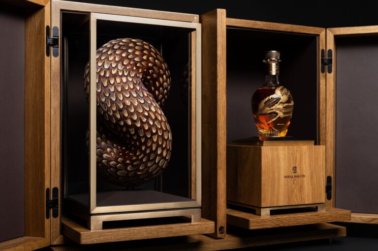 Socha z peří i karafa whisky jsou společně uloženy v ručně vyrobené dřevěné skříňce.